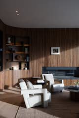 Inside, a curved wall of slatted walnut houses built-in bronze open shelving and a fireplace. 