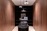 Continuing in the suite, we find boutique style his and hers dressing rooms. Hers features walnut slatted cabinets and a light velvet upholstery, White Onyx and bronze, his smooth walnut cabinetry with Belvedere stone and leather upholstery.