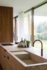 The kitchen features slatted walnut cabinets, a muschelkalk kitchen island with bronze taps and hardware.