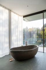 Two floor to ceiling glass panes with minimalist window frames draw in the surrounding forrest in which the home is located.