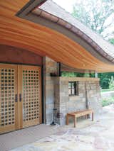 Exterior, Hipped RoofLine, Shingles Roof Material, Stone Siding Material, Glass Siding Material, House Building Type, Curved RoofLine, Wood Siding Material, and Metal Siding Material Front entry with curved wood ceiling  Photo 13 of 38 in Copper Fish Scale Home by Bjella Architecture