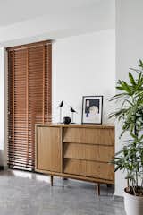 Oak veneer storage with recessed handles contributes to the minimal aesthetic. A pair of blackbird sculptures sit atop the unit while the greens liven up the space.