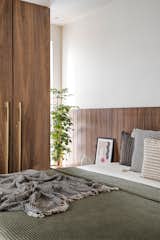 A sense of warmth envelops the bedroom filled with muted and neutral colour palette of browns and greens. Walnut stained wardrobe, pearl painted walls and textured bedding cocoon's the Parents' bedroom.