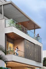 An overhanging linear space frame above the second-floor terrace acts as a distinctive crown, providing enclosure and character to the façade. Wooden-clad ceiling louvers on multiple levels introduce vibrant aesthetics, seamlessly blending warmth with modern design.