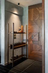 Hallway The entrance is a warm welcome home. A wooden door, stained a rich coffee bean brown, stands ajar. Intricate geometric patterns adorn the door’s surface,  like a secret message waiting to be unraveled.   Photo 14 of 16 in Trikon: A home of 3 materials by Design Search