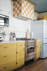 Kitchen, Engineered Quartz Counter, Range, Light Hardwood Floor, Ceramic Tile Backsplashe, Colorful Cabinet, Range Hood, Wood Cabinet, Microwave, Refrigerator, and Ceiling Lighting I splurged on a nice range and had fun designing the tiled hood with inexpensive tile.  Photo 3 of 28 in Cottage on Maybell by Maddie Hamilton