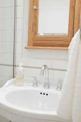 Bath Room, Corner Shower, Enclosed Shower, Pedestal Sink, Ceramic Tile Wall, Ceiling Lighting, Porcelain Tile Floor, One Piece Toilet, and Wall Lighting I added nooks where I could to make up for little surface area in the small 3-piece bathroom. The oak medicine cabinet off of Etsy is one of my favorite things in the house.   Photo 11 of 28 in Cottage on Maybell by Maddie Hamilton