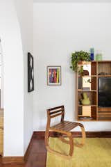 Living Room, Chair, and Medium Hardwood Floor The television stand, chair designed by Lia at college and paintings made by the children.   Photo 9 of 24 in Apartment on a building from 1948 in São Paulo. by Lia Soares Arquitetura