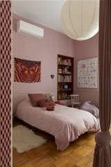Bedroom, Bookcase, Bed, Medium Hardwood Floor, and Pendant Lighting Iris's pink world, with its circus fabric.  Photo 15 of 24 in Apartment on a building from 1948 in São Paulo. by Lia Soares Arquitetura