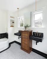 The original bathroom was transformed into a luxurious modern space with a nod to tradition. Retaining the original cast iron bath,  two elegant custom, handmade marble sinks were added with an innovative sliding mirror, positioned between the windows.