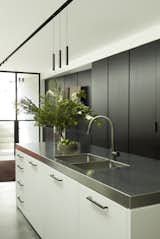 The stainless steel island in the modern, monochromatic rear kitchen