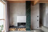 Living Room, Bench, Concrete Floor, Sofa, Wood Burning Fireplace, Track Lighting, and Coffee Tables The glaced brick open fireplace supplies warmth.  Photo 6 of 12 in Villa Kummelnäs by Sigrid Svensson