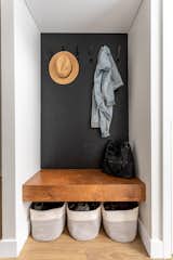 Coat hooks. Featuring a walnut floating bench and black textured vinyl wallpaper.