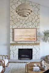 East Meets Westlake | Living Room 
Luxury interior home design, grand centered limestone fireplace with timber accent beam focal point, accompanied by wooden accents and custom linen upholstery furnishings, a large wicker lighting fixture all tied together with an earthy, tonal palette by Jubilee Interiors located in Westlake Village. 