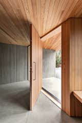A Douglas Fir pivot door makes for an impressive front entrance, while the board form concrete walls create cohesion between the exterior and interior.