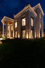 Located in an urban locality, the residence evokes a fusion of classical design with contemporary aesthetics. This is reflected in the design of the facade mimicking the essence of classical architecture with arched windows and Corinthian columns. Sleek lines and trabeated cornices define the style, adding a vintage look to the facade.
