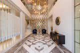 A striking chandelier drawing inspiration from classical styles casts a warm glow infusing a sense of drama into the space. 