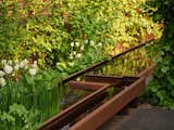 A striking water feature made from weathered steel is the central organizing element of the garden