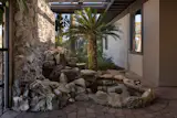 A small pond surrounded by rocks and flora is located near the home’s entrance. 