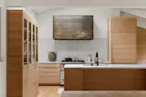 The kitchen features custom millwork, a painted metal hood, and oak cabinetry. 