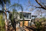 The house appears between trees and palmtrees. 