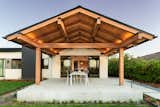 Covered outdoor living off of the kitchen, seen through sliding glass doors. Heavy timber beams span from interior to exterior throughout the project. Purlins were used instead of a ridge beam. Steel king posts were used instead of wood, which helps to exaggerate the purlins' flight towards the exterior.