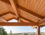 A gable roof provides shade for the patio. Heavy timber purlins were used instead of a ridge beam. The purlins sit on steel king posts to emphasize their gesture towards the view beyond. Knife plates connect the heavy timber posts to the beams above and patio below.