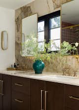 Stone backsplash makes an impact and makes a focal point in the Primary retreat bathroom. Mirrors placed in front of the windows help to accent the natural light coming into the space. 