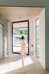 Mother and son open RAM pivot door to exit beautiful luxury home. 