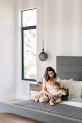 Mother and son read book on bed inside luxury home next to RAM casement window. 