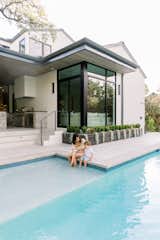 Mother and son sitting by pool in front of RAM picture window. 