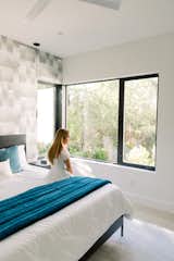 Girl sits on bed in front of RAM casement window with beautiful views of greenery outside. 