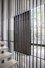 A modern entryway with unique door and floating stairs are illuminated by RAM picture windows.