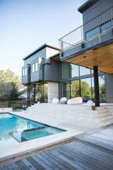 Modern home backyard is complete with pool, unique seating, and reflective RAM picture windows covering the back of the home.