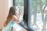 A girl looks out this RAM double casement window with a screen.