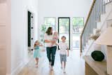 A family walks in the entryway of this transitional Dallas area home featuring RAM front swing door and windows with modern grids.