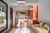 The compact and functional kitchen area anchors the space.  
An accent wall in terracotta hue with a concealed door hides a bathroom within.