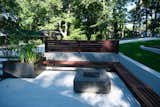 Modern concrete patio space with fire pit, enclosed by retaining wall with built-in seating. The welded steel planter gives a nice contrast and is an opportunity to add greenery.