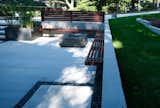 Modern concrete patio space with fire pit, enclosed by retaining wall with built-in seating. The welded steel planter gives a nice contrast and is an opportunity to add greenery.