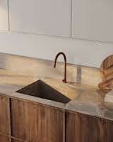 The light wood tone of the cabinet doors pairs effortlessly with the sandy hue of the Dekton countertop, creating a warm and natural look that is easy to love and a popular choice for modern kitchens.