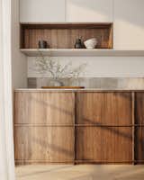 The custom shelving system combined with handleless hinged cabinets delivers a well-designed, space-efficient storage solution that optimizes every inch of the compact kitchen layout.