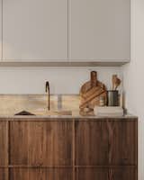 The warm shade of oak provides a subtle yet striking contrast to the kitchen's creamy white cabinets, adding depth and visual interest to the design. The combination of natural wood and neutral tones underscores the calm, minimalist aesthetic of the kitchen.