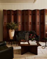 Our goal for this space was to create a cozy breakaway area for our clients to work from home, with a warm and inviting atmosphere similar to a library. However, we wanted to achieve this without breaking the bank on expensive mahogany paneling. Since this was a second home for the clients, we needed to find a cost-effective strategy. After some research, we discovered these beautiful mahogany room dividers from one of our vintage vendors, and they became the focal point of the room. We then complemented them with a mid-century Hans Olsen settee and chairs, a French 1930s coffee table, and a hand-woven rug from Nepal. The combination of these elements created the perfect ambiance we were aiming for.
