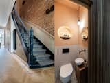The wall in the stairwell has been completely exposed in the original red brick. The playful positioning of sconces accentuates the whimsical character of the brick wall.