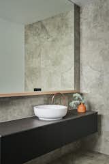 An earthy blend of stone, timber and copper in this guest bathroom in the Torquay Garden House by Lifespaces Group