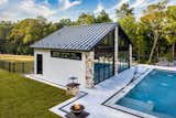 A pool house turned into a home gym that features a sauna, bathroom, and views of the pool 