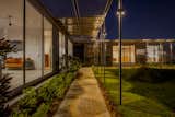 A black kadapa stone pathway, designed for its raw aesthetic and drainage efficiency, is lit with bollards and custom pole lights, enhancing functionality and ambiance.