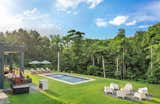 Backyard oasis with a sleek salt-water pool and a cozy firepit area, seamlessly integrated into the lush greenery of the surrounding forest.
