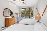This serene bedroom features two queen beds with picturesque views of the front and back patios. The space is bathed in natural light and fresh air, thanks to a thoughtful combination of jalousie and projected windows, which maximize ventilation and illumination. Warm wooden furniture and decor, a hallmark of Cabaña Serena’s design, add an organic and inviting touch. The room’s minimalist aesthetic seamlessly blends comfort and nature, creating a tranquil retreat for guests.