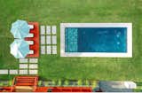 Aerial view of a modern backyard oasis designed with meticulous attention to detail. Featuring Corten steel planters accented by fine gravel,  pampas grass and multiplex bamboo. At the heart of the space is a sleek saltwater pool with elegant tilework, complemented by a sunbathing deck with vibrant tones and shaded by umbrellas. Concrete pavers create a clean, geometric pathway, seamlessly blending functionality with minimalist aesthetics.